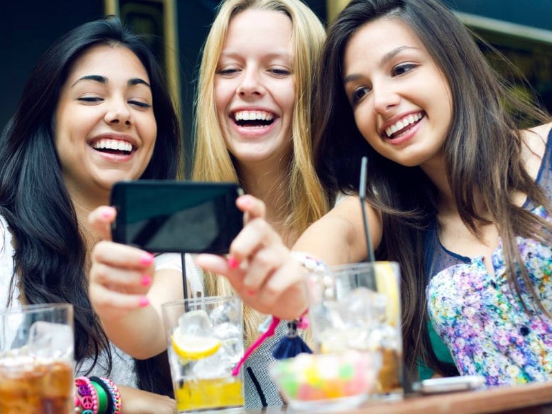 Several women taking a selfie in front of their cocktails