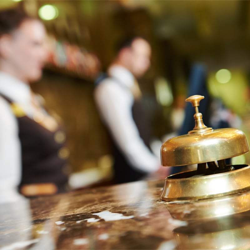hotel front desk staff with a service bell in the foreground