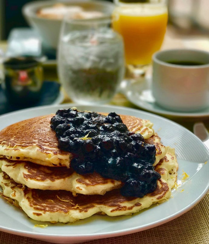 a stack of pancakes with blueberry sauce poured on top