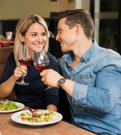 man and woman making a toast over plates of food