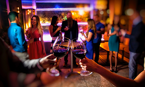 two people clinking wine glasses in front of a classy club scene background