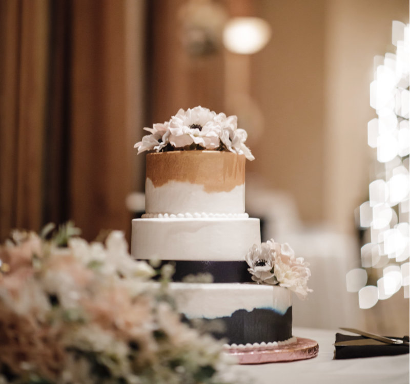 A shot of a three-tiered wedding cake, in brown, white and black.