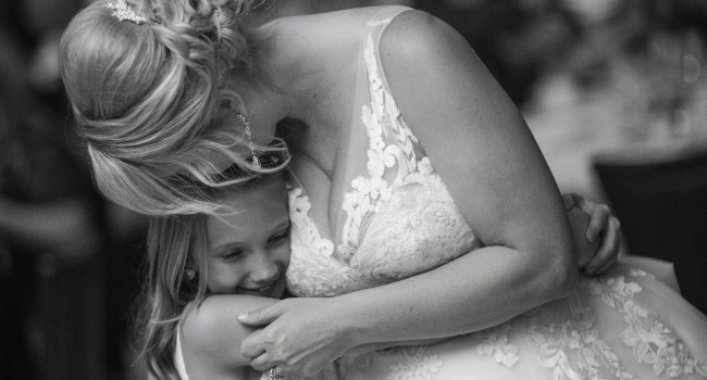 A black and white shot of a bride hugging a young girl.