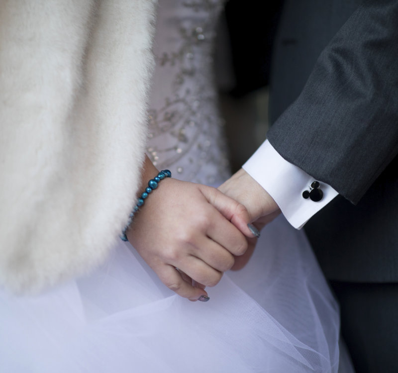 A clsoe-up shot of a bride and groom's hands, highlighting the Disney-themed shirt-cuffs of the groom.