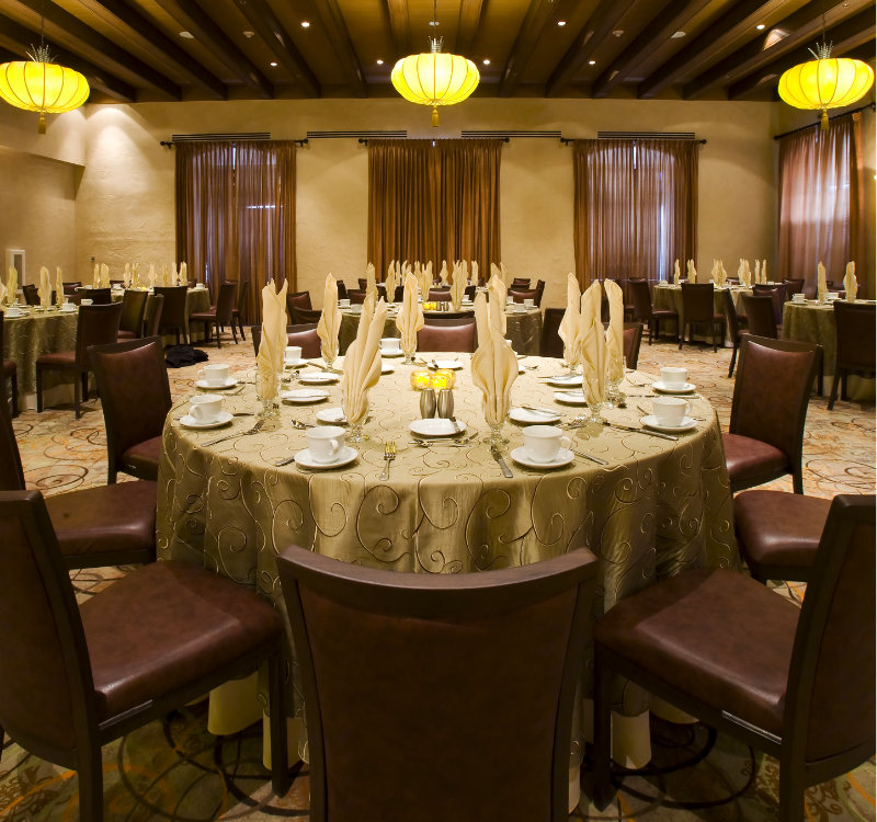 An image of the Casablanca room adorned with yellow paper lanterns, set for a wedding dinner, in white and gold.